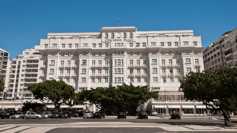 Vista diurna do Hotel Copacabana Palace no Rio de Janeiro, com sua clássica fachada branca e arquitetura elegante.