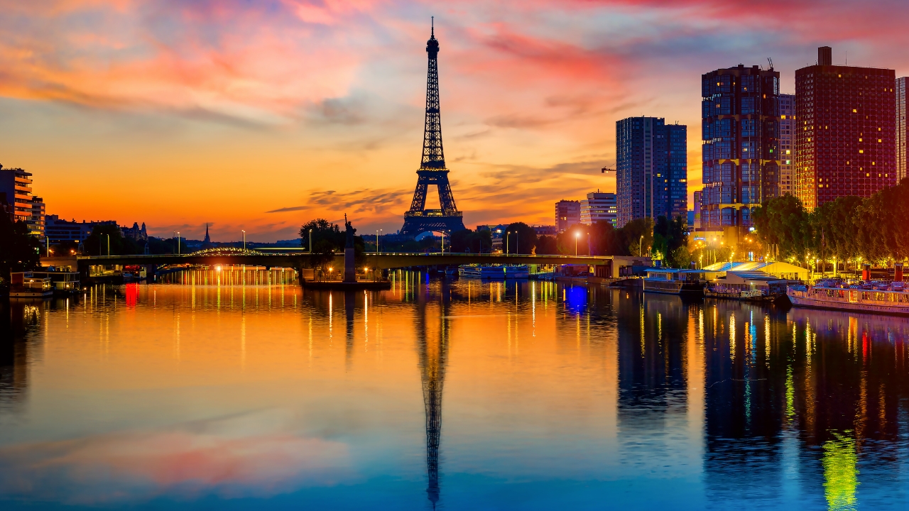 Anéis olímpicos iluminando o horizonte de Paris, representando a unidade durante os Jogos