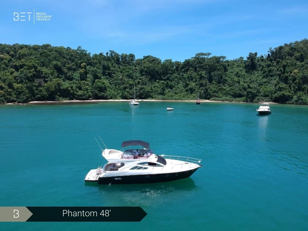 Iate Phantom 48' com solário à proa e vista panorâmica de Angra dos Reis.