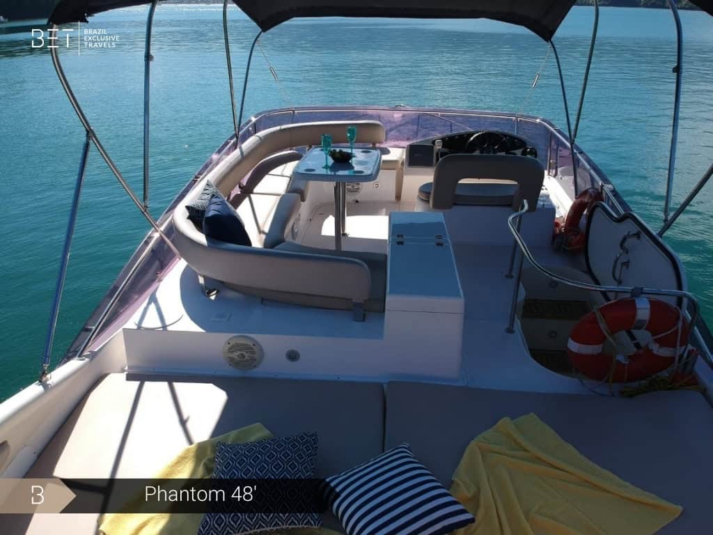 Iate Phantom 48' com solário à proa e vista panorâmica de Angra dos Reis.
