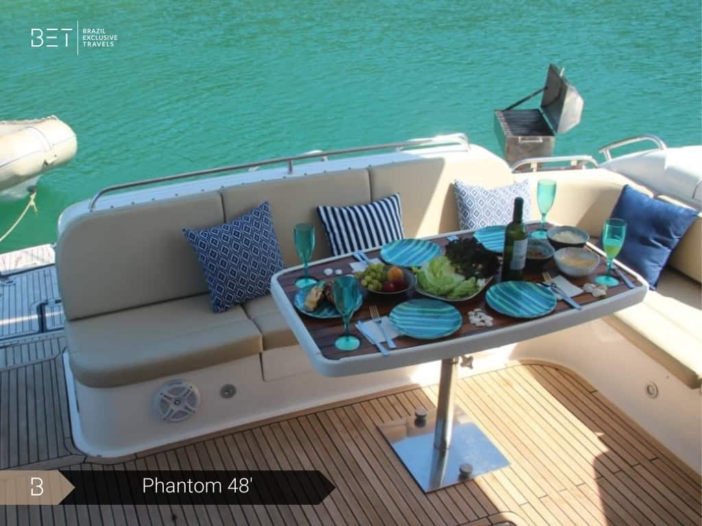 Iate Phantom 48' com solário à proa e vista panorâmica de Angra dos Reis.