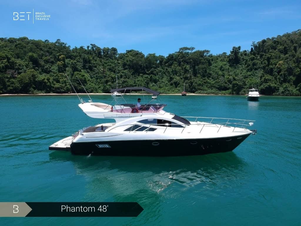 Iate Phantom 48' com solário à proa e vista panorâmica de Angra dos Reis.