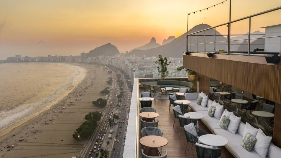 Beachfront view of Copacabana from the rooftop pool of the Hilton Rio de Janeiro Copacabana, with sun loungers and ocean in the background.