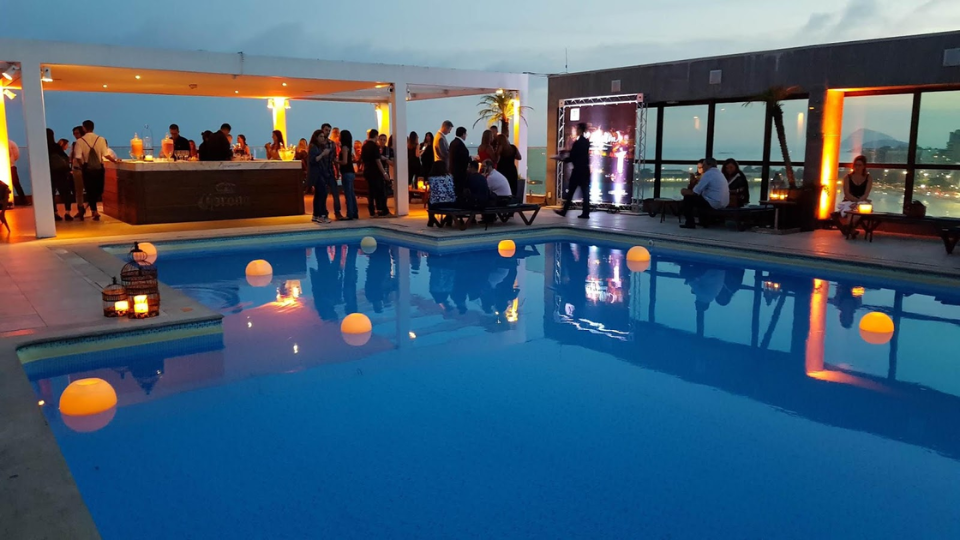 Sunset party at the rooftop pool of Pestana Rio Atlântica, with people enjoying music, drinks, and panoramic views of Copacabana Beach.