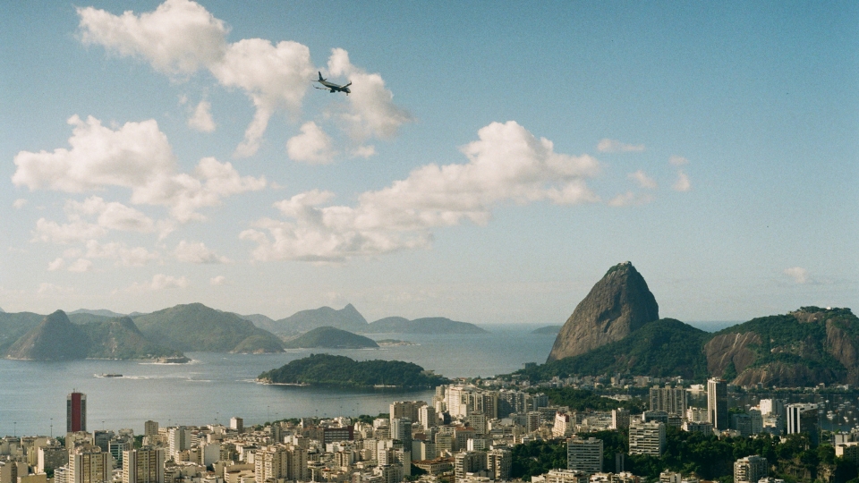 Plane Tickets to Rio de Janeiro_ A Concierge Guide for High-End Travelers (2) View of Rio de Janeiro with Sugarloaf Mountain on the right and an airplane flying in the sky