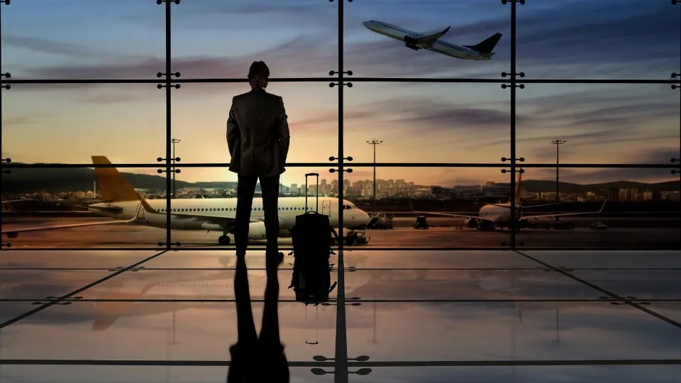 Business traveler watching airplanes take off from the runway - flight booking for corporate travel