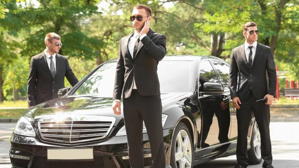 Group of professional bodyguards standing in front of a luxury Mercedes, representing private security services for high-end travelers.