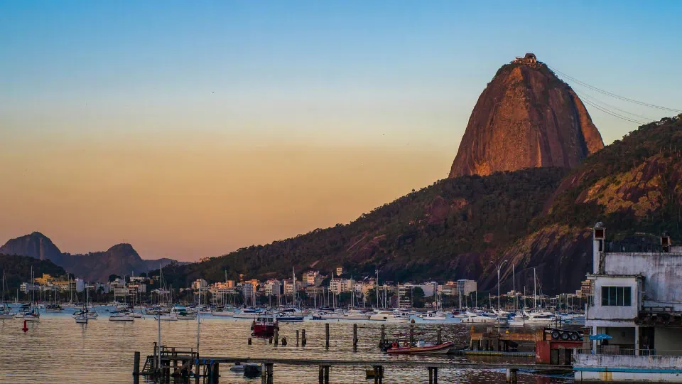 Sports Exclusive Travels - Homepage - Events (2) Sugarloaf Mountain at sunset in Rio de Janeiro, Brazil, with golden light over the bay.