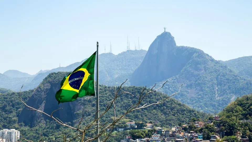 Brazilian flag waving with Christ the Redeemer in the background, symbolizing vip travel and authentic travel experiences across Brazil’s most iconic destinations.