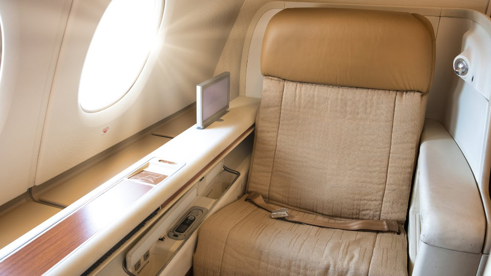 First-class airline seat with soft lighting and window view, illustrating long-haul comfort for Canada travelers booking Brazil flights through a luxury travel agency.