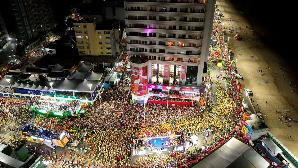 Carnival parade in Salvador with live music trucks and crowds following the procession along the coastal avenue