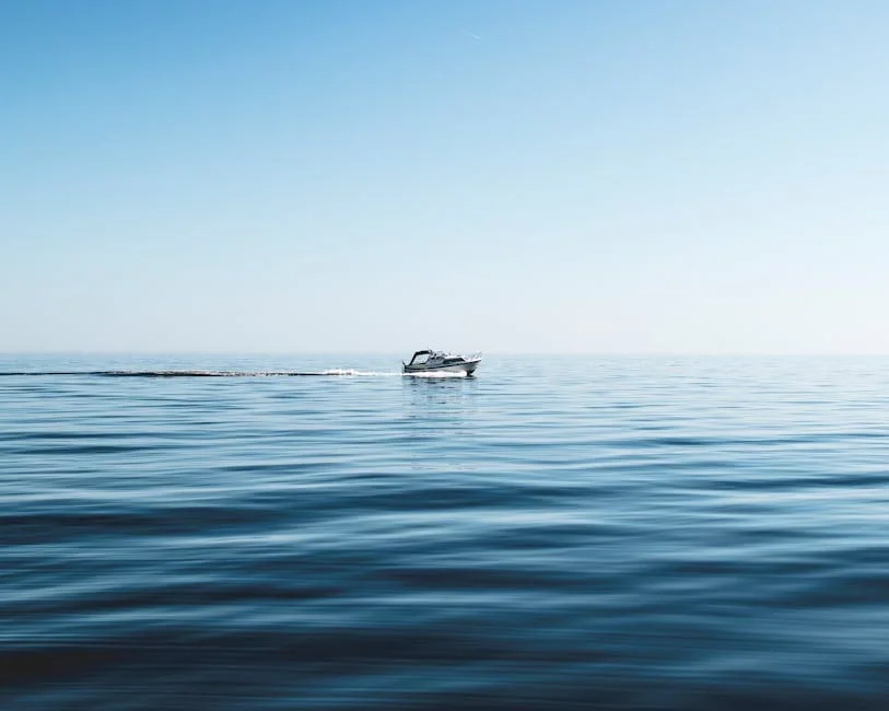 A lone boat cruising through calm ocean waters under a clear blue sky.