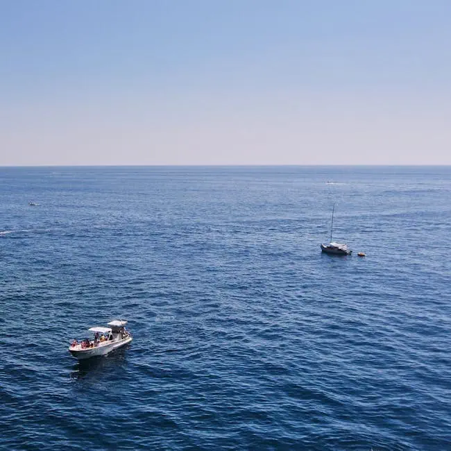 pexels-photo-21300315-21300315 Aerial shot of boats sailing on a vast blue ocean under a clear sky.