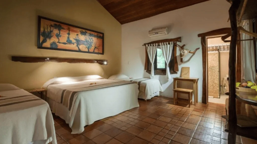 Araras Ecolodge - Hotel Booking in the pantanal (7) Interior of a rustic bedroom at Araras Ecolodge with wooden ceiling and terracotta tile floor.