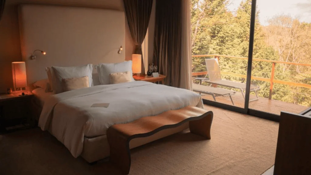 Botanique Hotel Experience - Hotel Booking in Sao Paulo (8) Bedroom with large bed, bedside lamps, and balcony with view of trees and sky.
