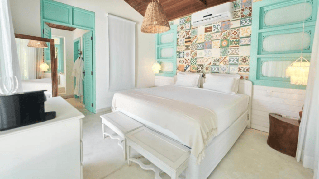 Casa Brasileira Hotel - Hotel Booking in the northeast (12) Bright bedroom with white bed, colorful tiled wall, turquoise window frames, and wicker pendant lamp.