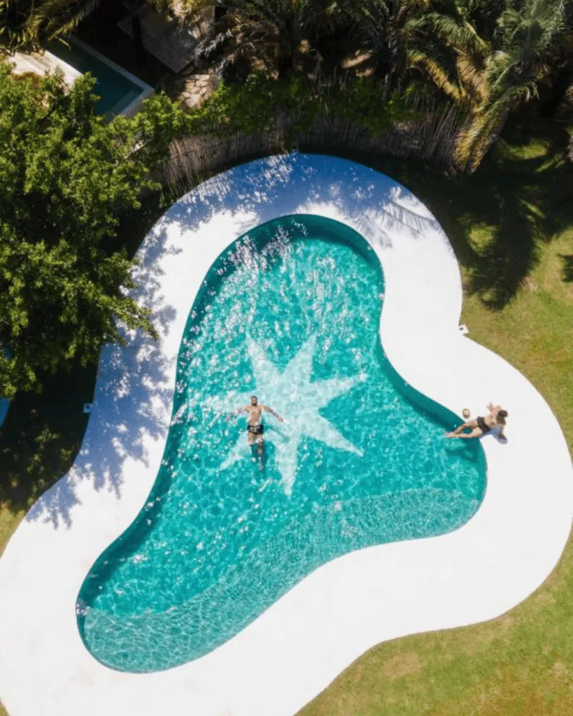 Casa Brasileira Hotel - Hotel Booking in the northeast A swimming pool with a star-shaped design in the center, surrounded by lush greenery.