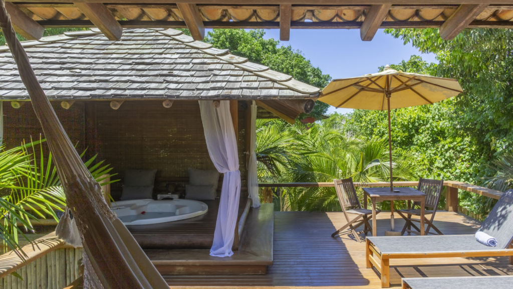 Estrela d agua - Hotel Booking in Trancoso (6) Private outdoor deck with a hot tub, table, and umbrella at Estrela d'Agua in Brazil.