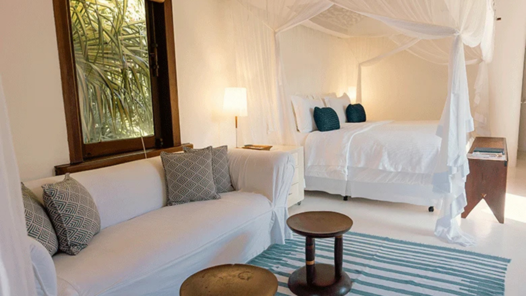 Estrela d agua - Hotel Booking in Trancoso (7) Luxurious bedroom with a four-poster bed and a sitting area with a sofa and pillows.