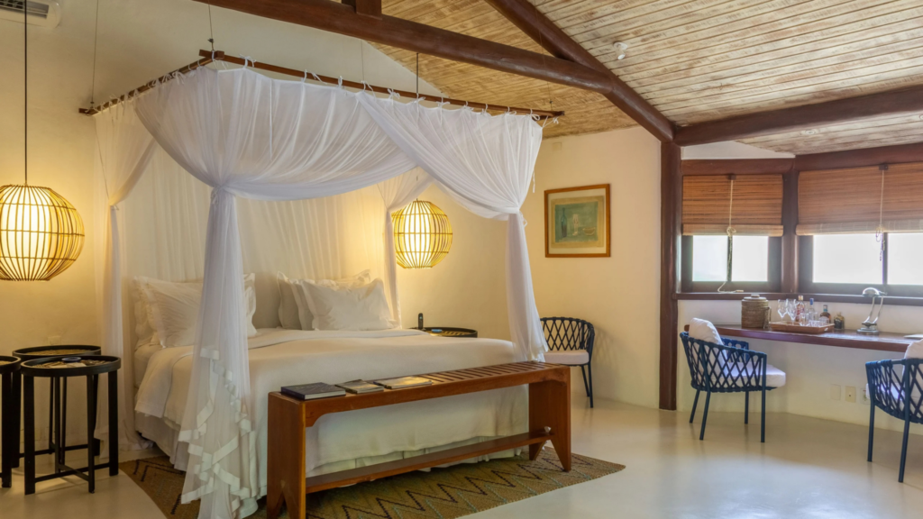 Estrela d agua - Hotel Booking in Trancoso (8) Luxurious bedroom with four-poster bed, mosquito net, and wooden ceiling in a tropical villa.