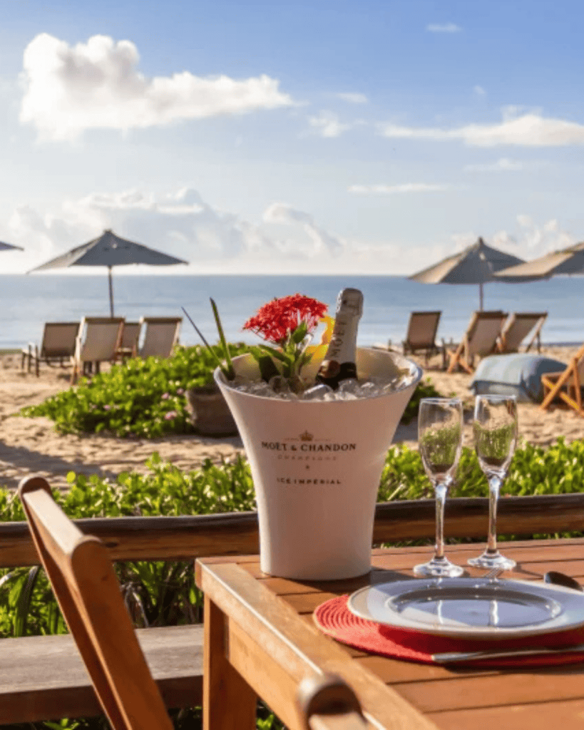 Estrela d agua - Hotel Booking in Trancoso Beachside dining setup with champagne and view of the ocean and umbrellas.