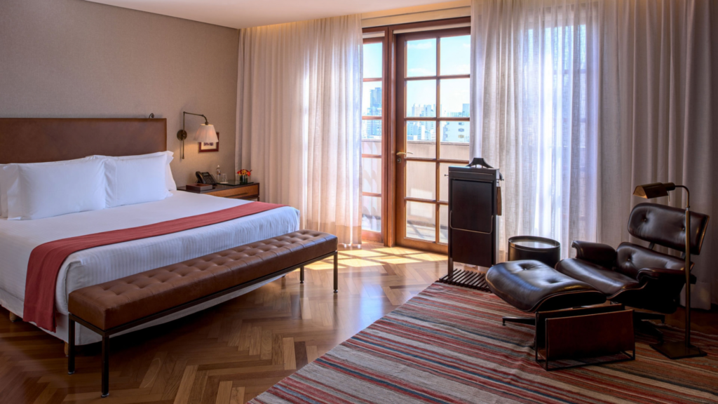 Fasano São Paulo - Hotel Booking in Sao Paulo (7) Hotel room with a large bed, wooden floor, and balcony with city view.
