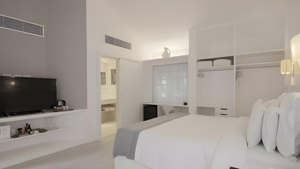 Unique Garden - Hotel Booking in Sao Paulo (8) Modern bedroom with white walls, bed, and built-in storage in a hotel or villa.